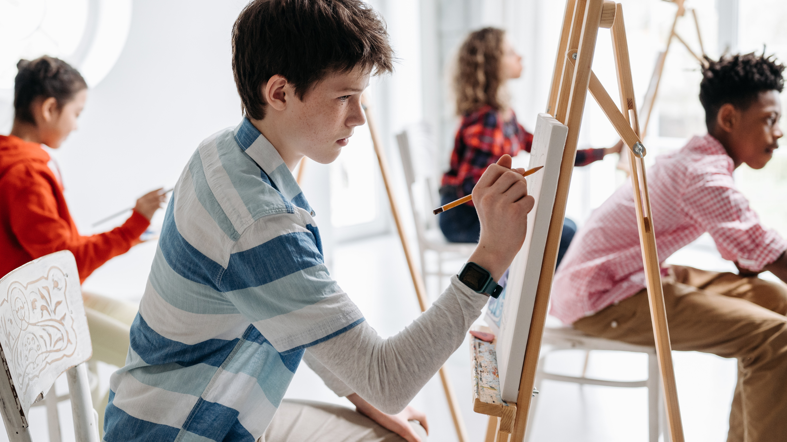 Kids drawing at easels in art class